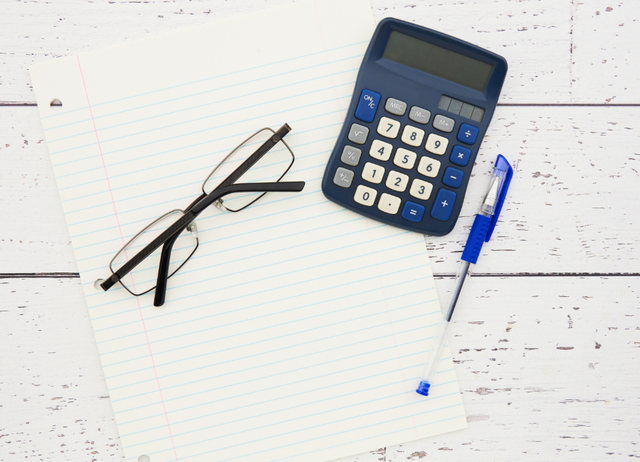 Calculadora, óculos e caneta sobre documentos
